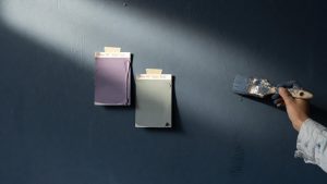 Mur peint en bleu gris foncé, texture mate de peinture éclairée par lumière rasante mettant en relief coups de pinceau