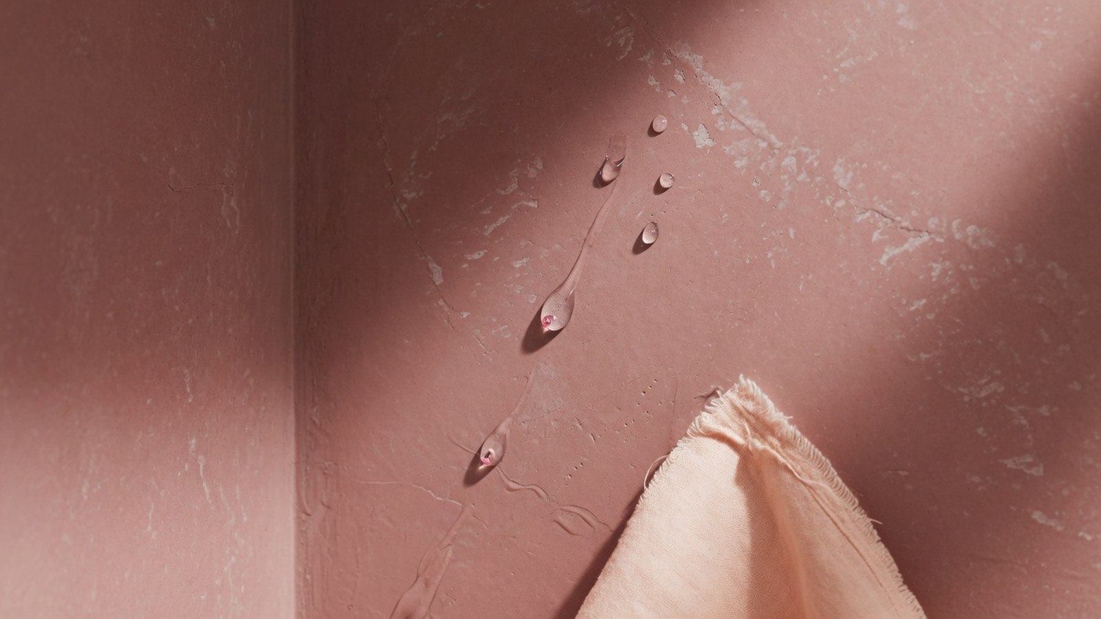Coin de mur de douche rose poudré avec finition mate texturée et gouttes d'eau perlant