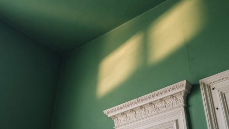 hero-1 Coin de pièce en gros plan : mur et plafond peints du même vert foncé, jonction floue, lumière du matin douce.